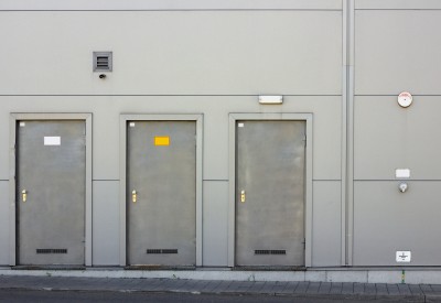 Gray metal wall and three armor doors. Small video camera over an entrance