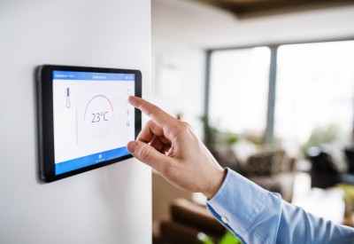 An unrecognizable man pointing to a tablet with smart home control system.